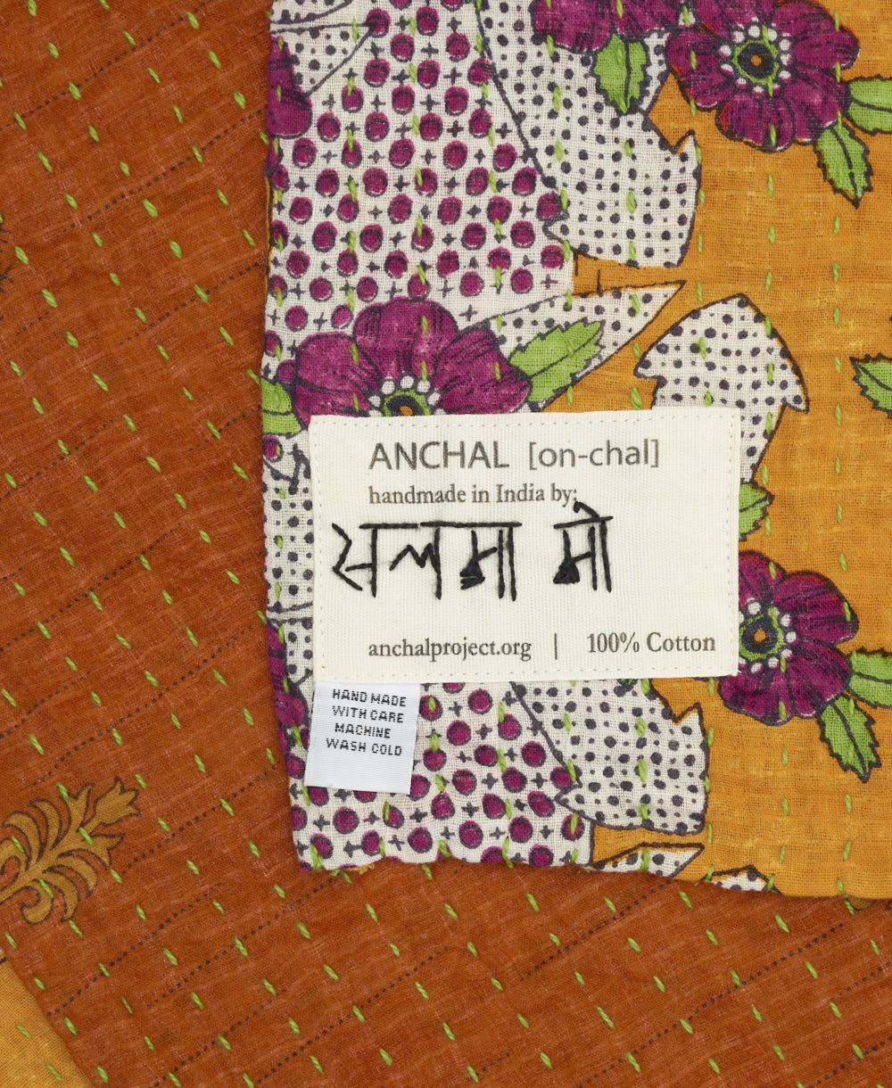 small kantha blanket with signature of the artisan maker on the tag