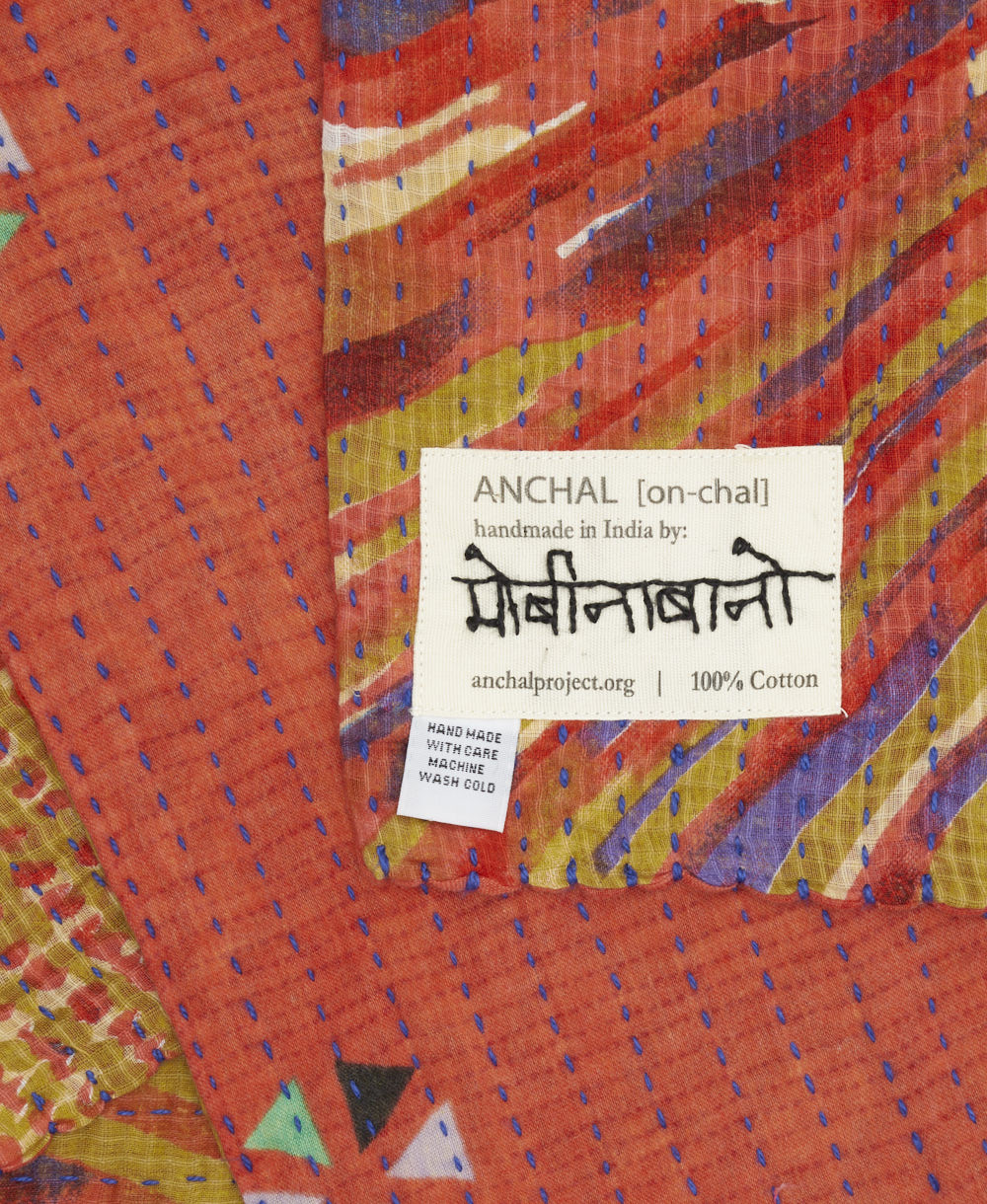 small kantha blanket with signature of the artisan maker on the tag