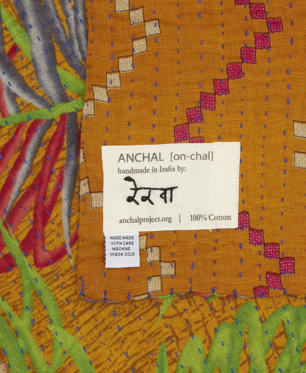 small kantha blanket with signature of the artisan maker on the tag