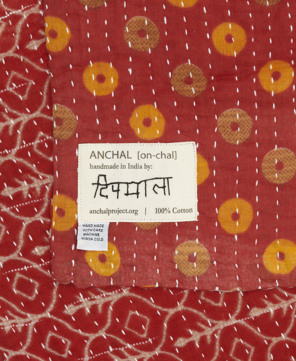 small kantha blanket with signature of the artisan maker on the tag
