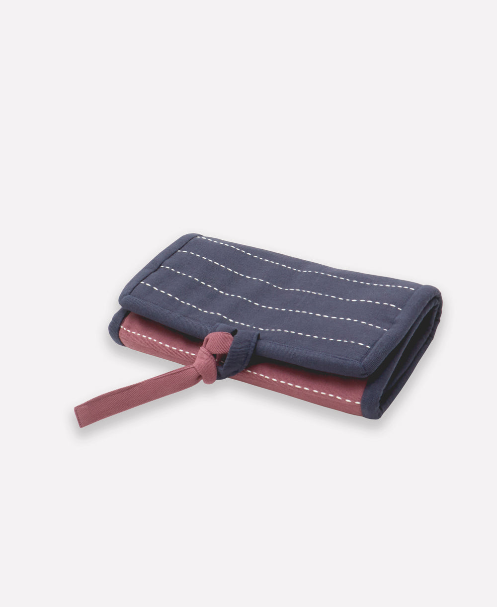 small travel organizer folded up in shades of navy blue and plum purple tied together