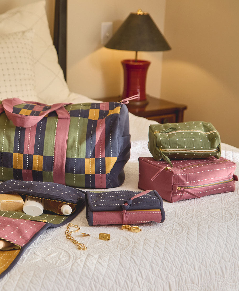 folded hanging toiletry bag sitting on white bedspread