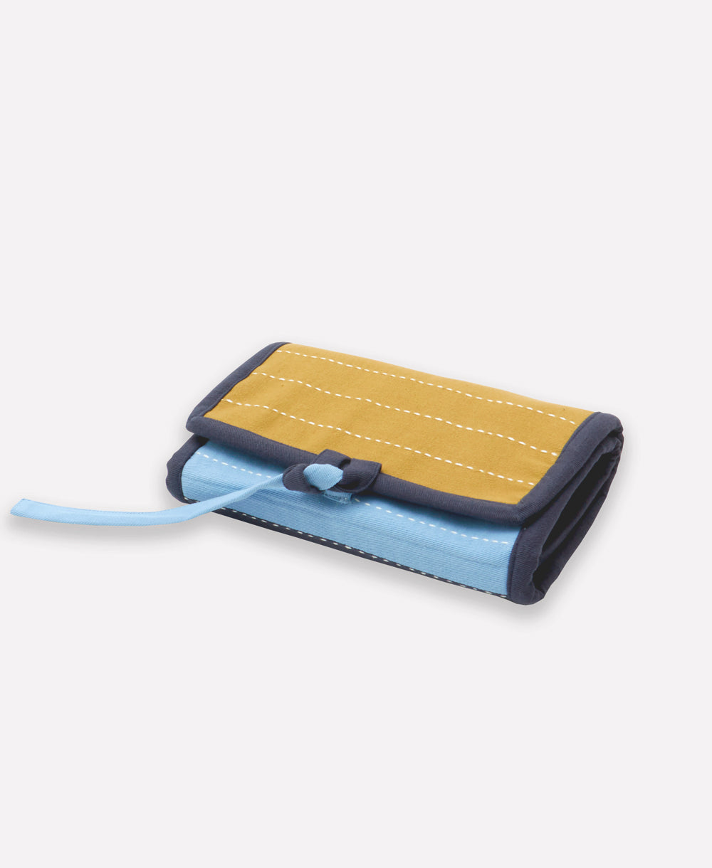 small folded travel organizer made from organic cotton in shades of navy, ochre yellow and sky blue