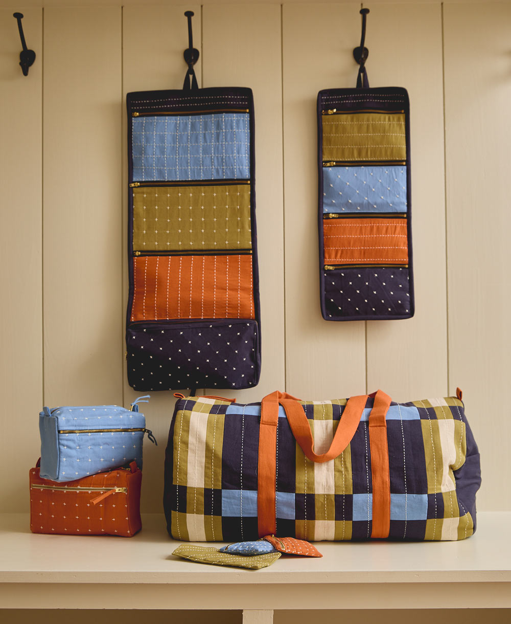 hanging toiletry bag travel organizers hanging on black wall hooks against a white wall with a matching duffle bag
