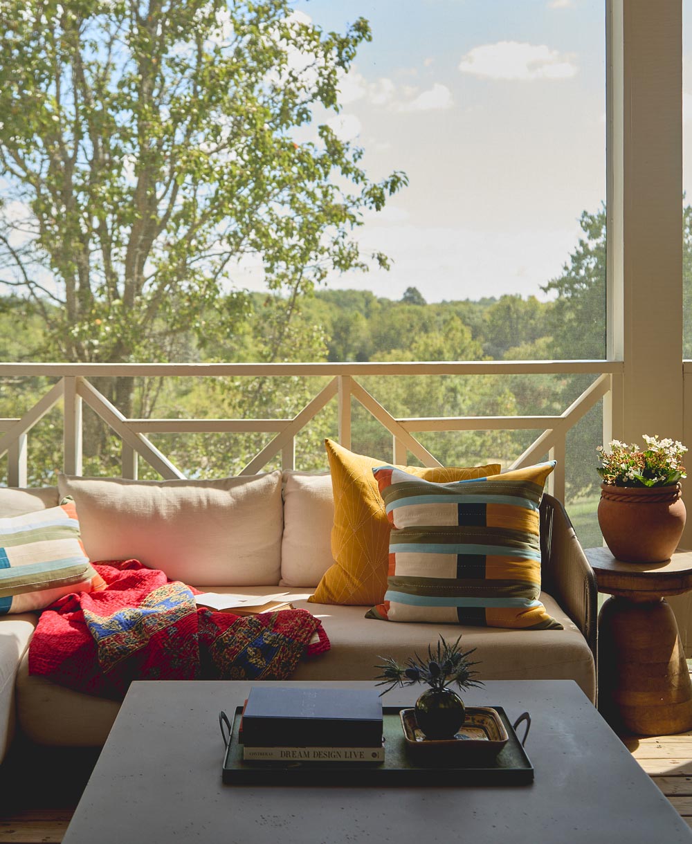 Living room with a couch adorned with colorful pillows and a view of trees outside