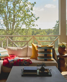 Living room with a couch adorned with colorful pillows and a view of trees outside