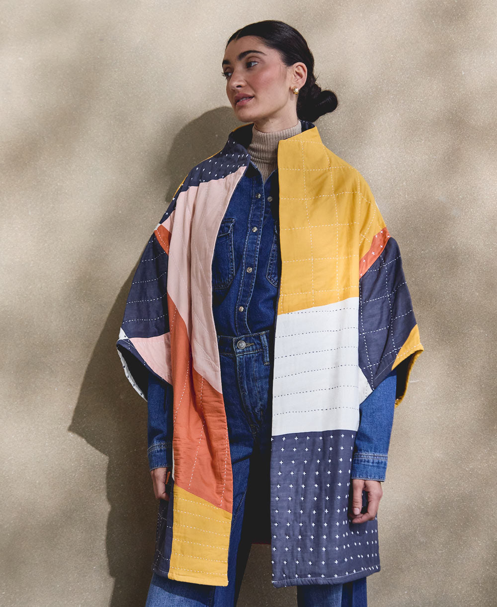 woman wearing all denim outfit with colorful quilted jacket made from 100% organic cotton and embroidered by hand in India