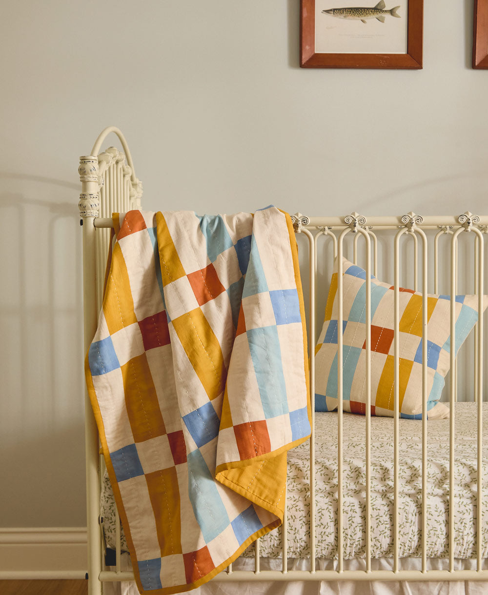 Colorful patchwork quilt draped over a crib in a nursery setting