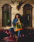 woman sitting on red leather couch holding checkered tote bag 