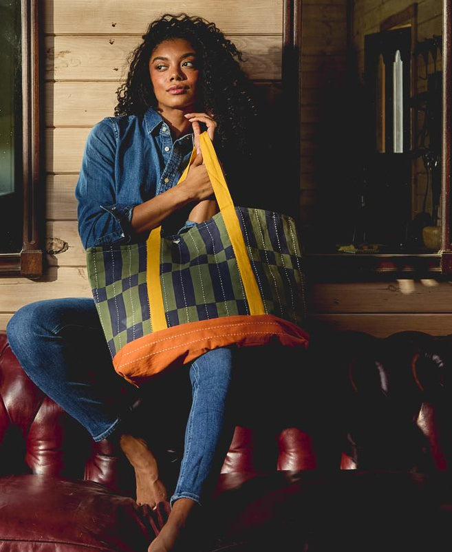 woman sitting on red leather couch holding checkered tote bag 