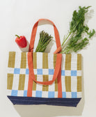 Tote bag with checkered pattern filled with groceries on a white background