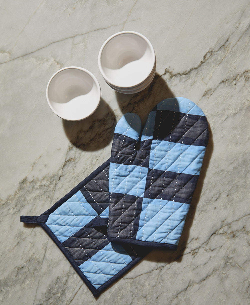 quilted pot holder and matching oven mitt in dusk blue and navy blue sitting on grey countertop
