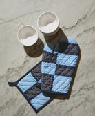 quilted pot holder and matching oven mitt in dusk blue and navy blue sitting on grey countertop