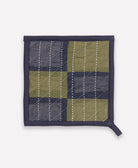 Quilted square hot pad with green and navy checkered pattern on a white background