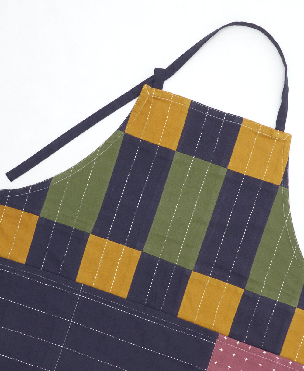 Checkered apron with a pattern of green, yellow, and navy squares on a white background