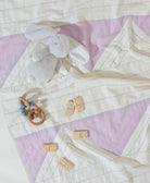 Quilt with baby toys on a purple and white checkered background
