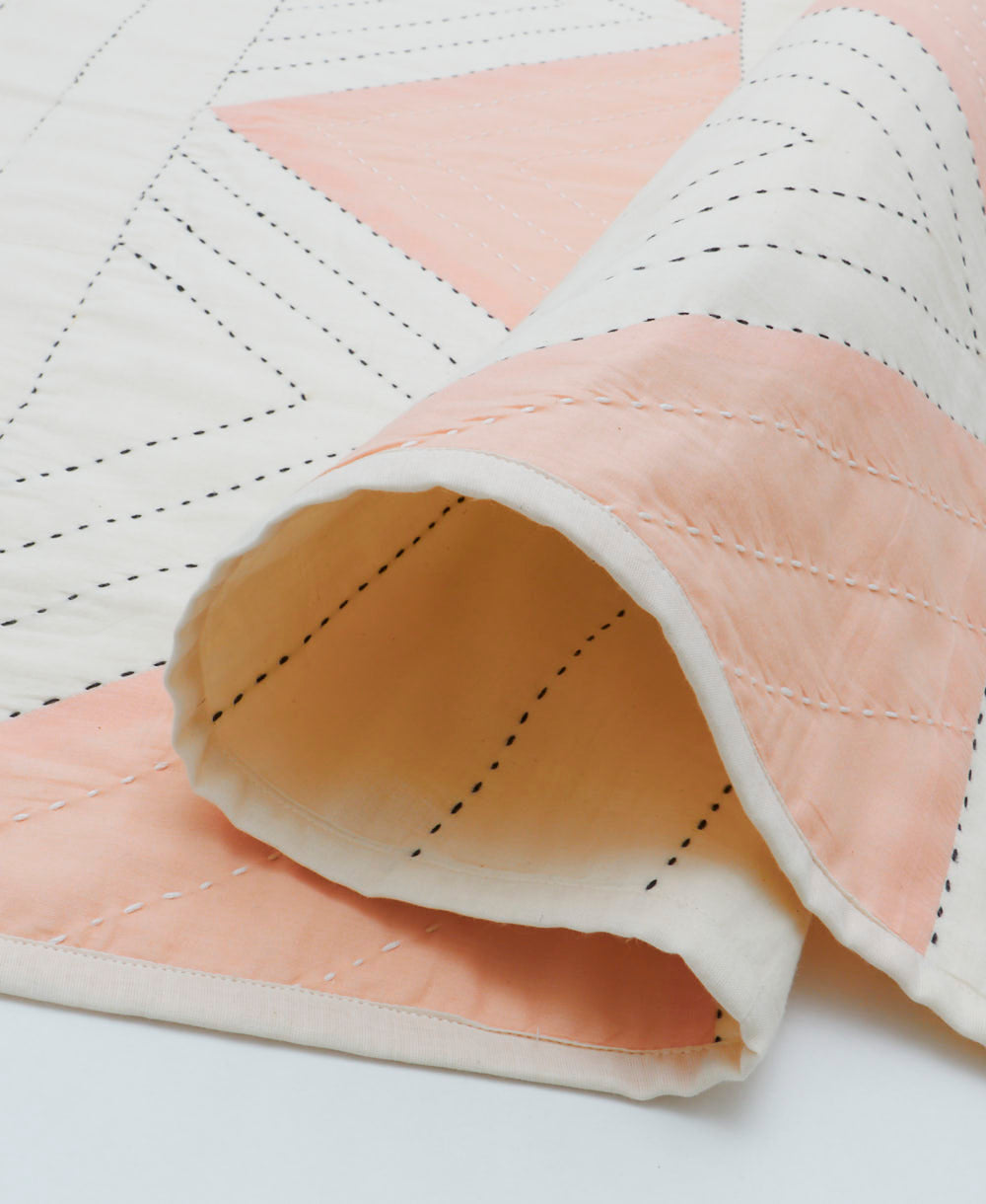 Quilted fabric with pink and white diamond pattern on a light background