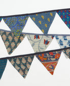 Colorful fabric triangle banner with various patterns on a white background