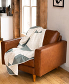 quilted throw blanket with geometric triangle design draped over chestnut leather armchair