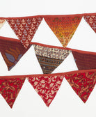 Decorative fabric triangle banner with brown and red patterns on a white background