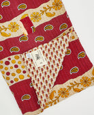 Kantha quilt throw with a tag featuring the hand-stitched signature of the maker