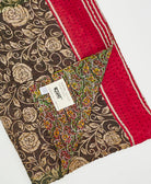 Kantha quilt throw with a tag featuring the hand-stitched signature of the maker