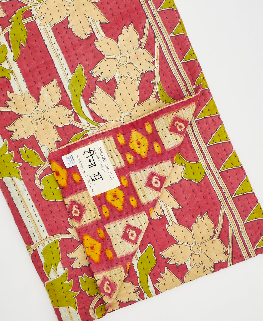 Kantha quilt throw with a tag featuring the hand-stitched signature of the maker