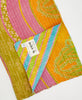 Kantha quilt throw with a tag featuring the hand-stitched signature of the maker