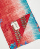 Kantha quilt throw with a tag featuring the hand-stitched signature of the maker