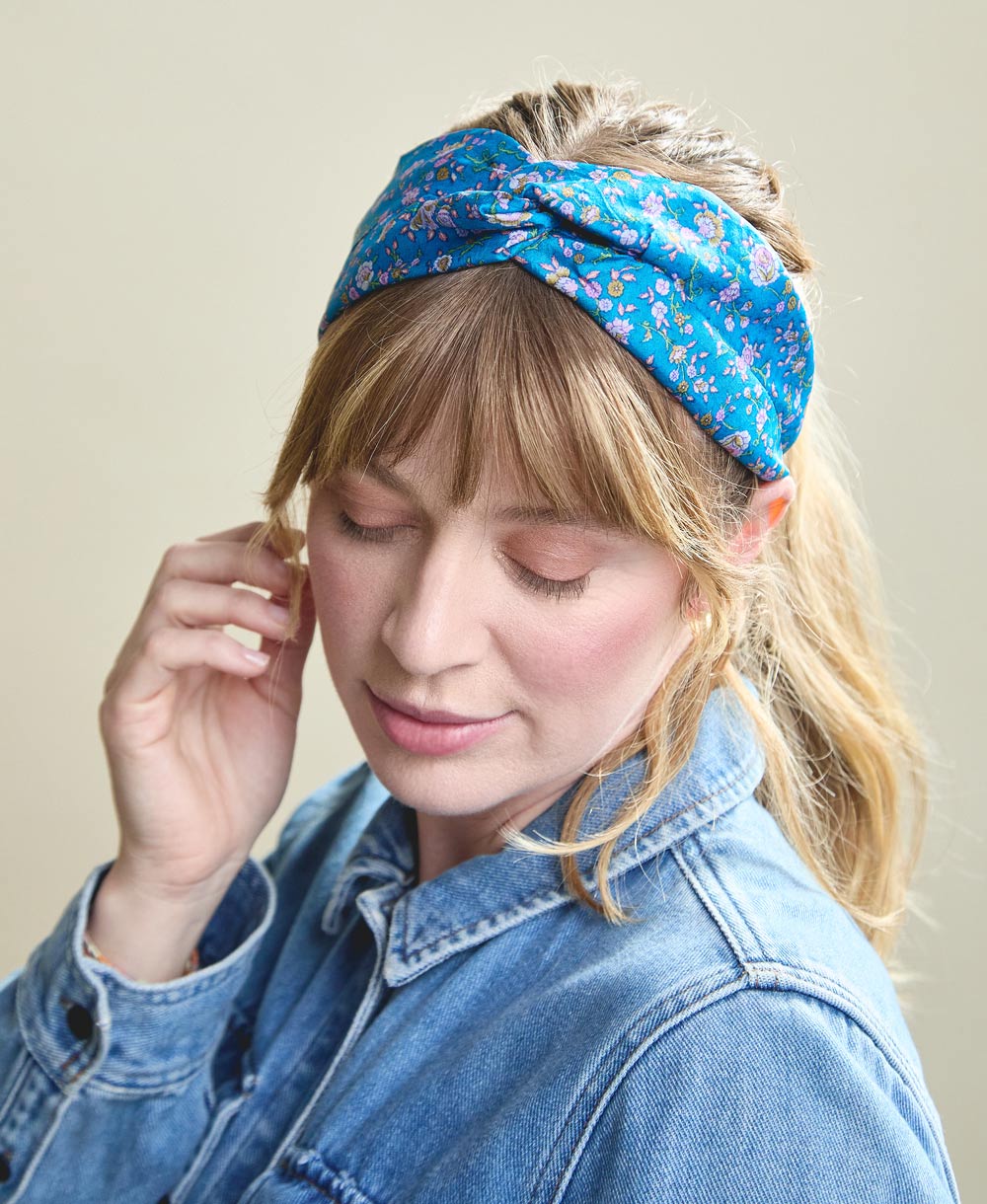 blonde woman with bangs wearing blue floral silk twist headband