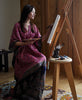Woman wearing vintage pink silk kaftan dress painting at an easel 