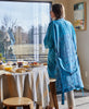 woman wearing a blue paisley vintage silk robe
while making breakfast in her kitchen