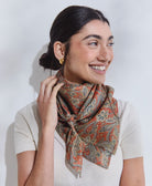 orange paisley silk square scarf tied uniquely around woman's neck