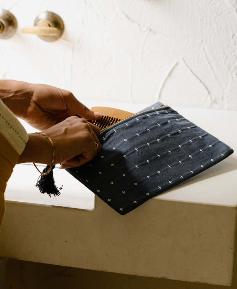 Cross-stitch small pouch made with organic cotton being used in a bathroom holding a comb