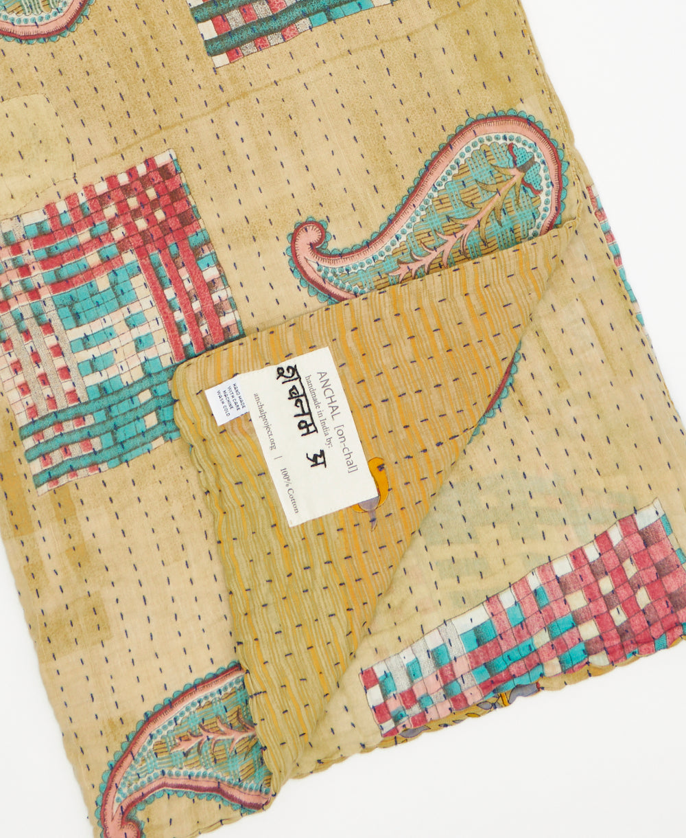 beige kantha quilt throw featuring the handstitched signature of the maker 