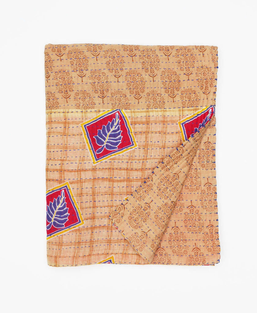 Light tan traditional patterned small throw blanket that has a bright purple leaf design creating contrast 