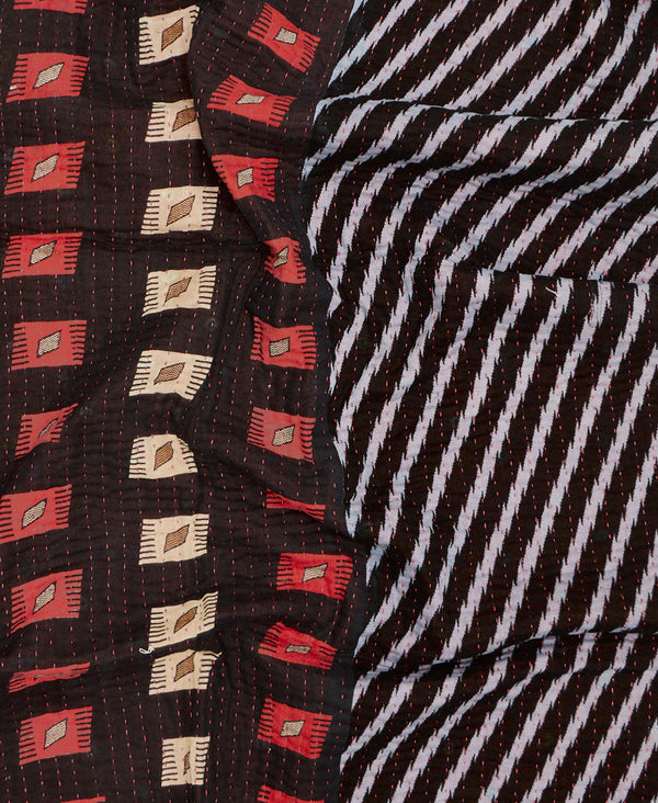 Black small quilt throw featuring contrasting patterns in white and red and red kantha hand stitching 