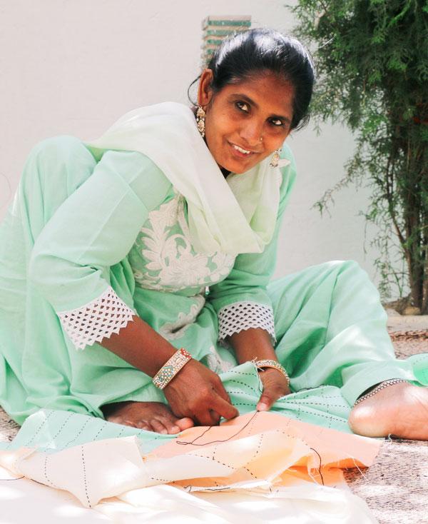 Anchal Project artisan Madina hand stitching a patchwork pillow