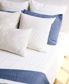 modern boho throw pillow arrangement in all white with slate blue accents