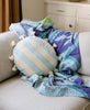 cloud blue cabana stripe round throw pillow and a blue kantha quilt on an ivory couch