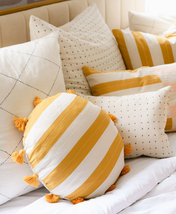 yellow striped throw pillow on a bed full of soft white pillows