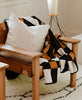 white cross-stitch modern throw pillow in vintage rattan chair for modern boho look