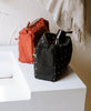 charcoal black and rust orange toiletry bags made from organic cotton on modern square sink