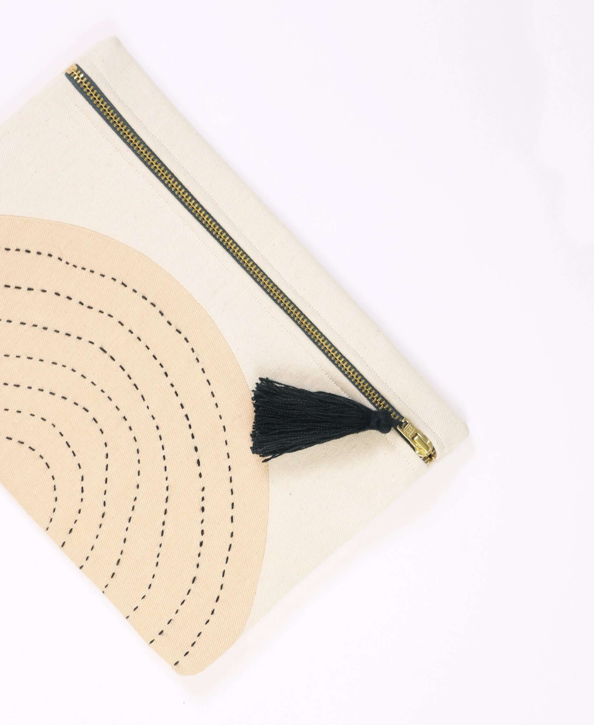 Beige and charcoal hand stitched small pouch that has a tassel detail