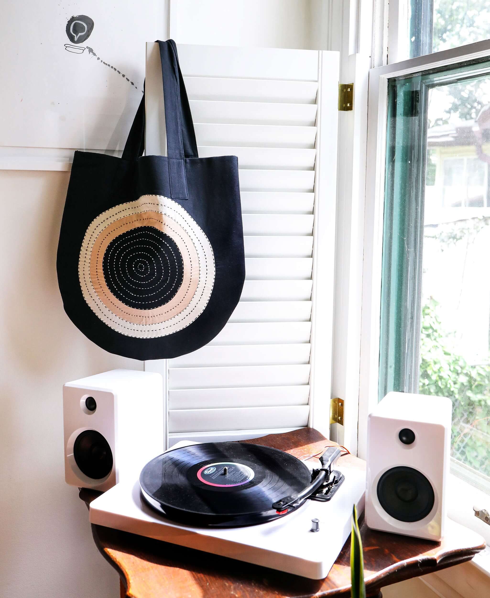 black canvas tote bag hanging on door by window