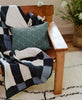 handmade organic cotton graph pillow in spruce styled on leather chair with a the plaid quilt throw
