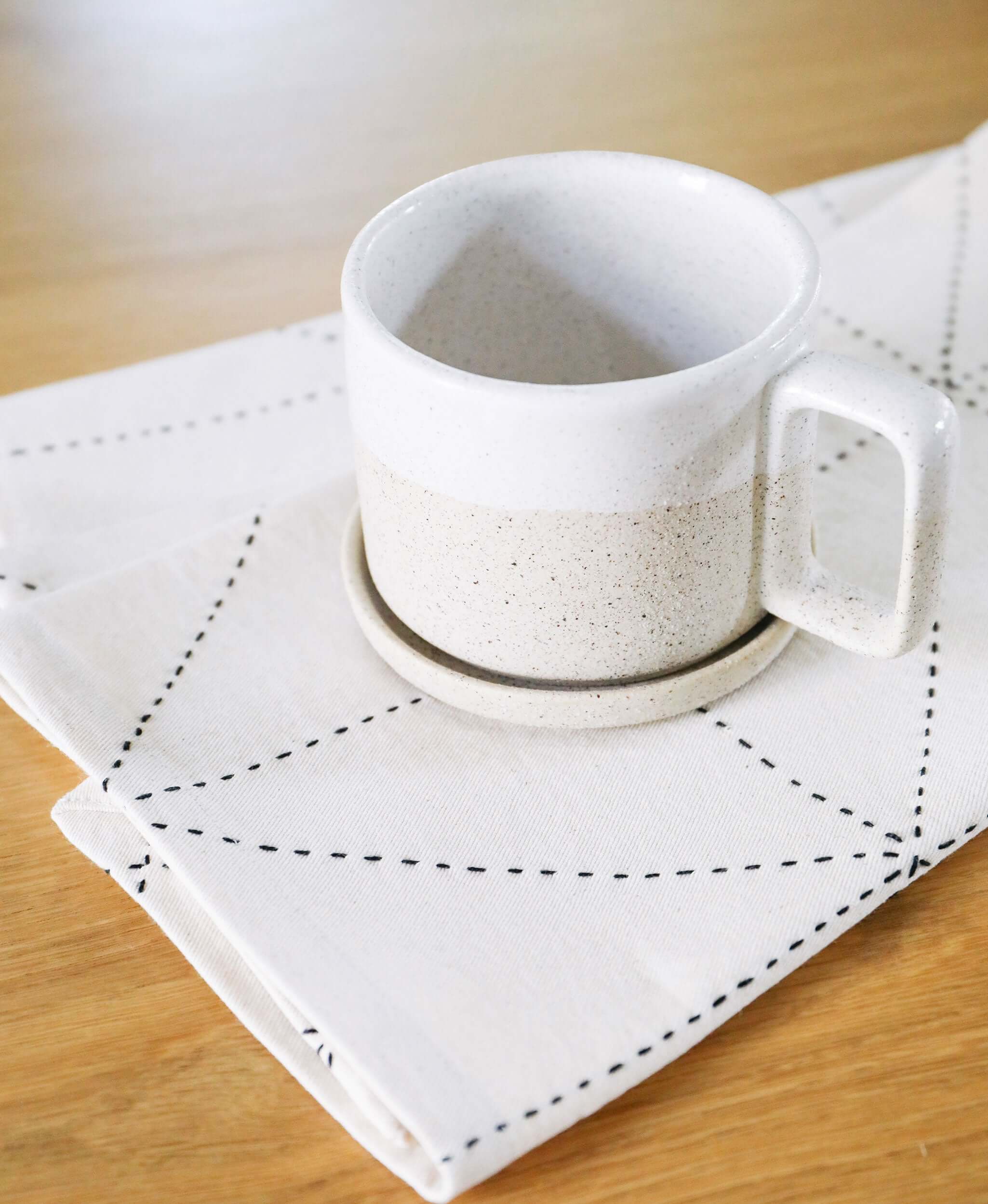 Close up shot of geometric ivory tea towel with ceramic coffee cop