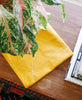 Mustard yellow tea towel styled in home with plants
