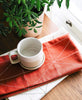 Red and white stitched tea towel paired with bone geometric tea towel both made with organic cotton
