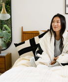 woman sitting on all white bed with black and white lumbar pillow in charcoal